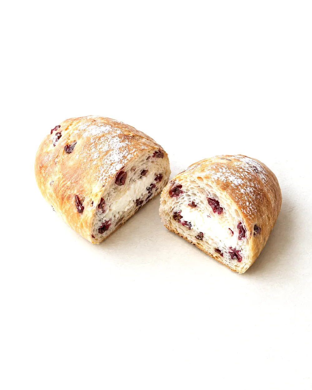 Concept image of cranberry cream cheese bread: an oval loaf with red cranberries, cut in half to show a white cream cheese center.
