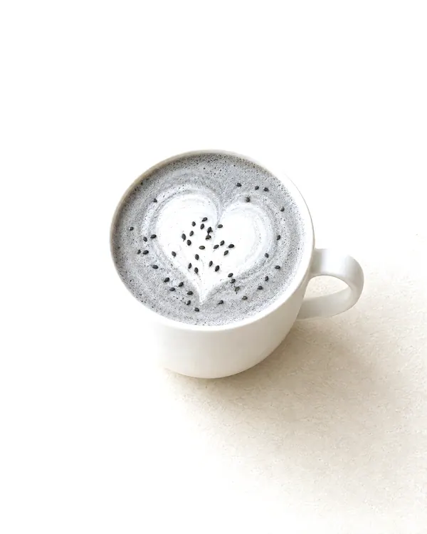 Concept image of a white cup of pale gray latte with a latte-art heart.