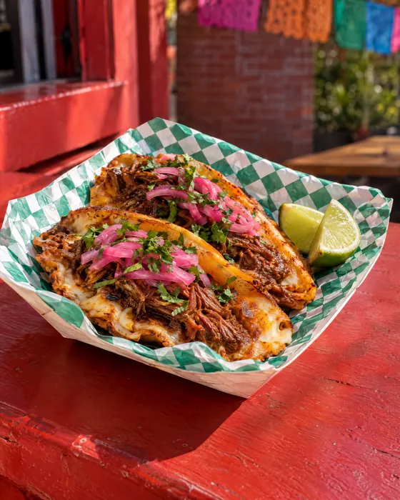 Queso birria tacos with pickled onions and cilantro.