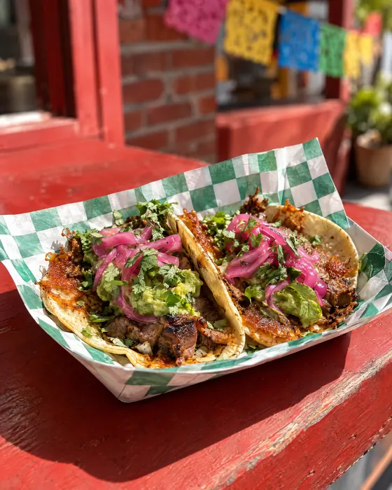 Super street tacos with carne asada, guacamole and pickled onions.