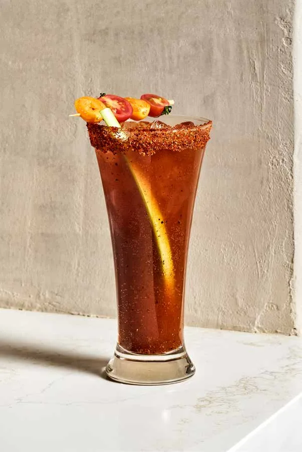 Michelada de Casita in a tall pilsner glass with a chile-salt rim and cherry tomato skewer