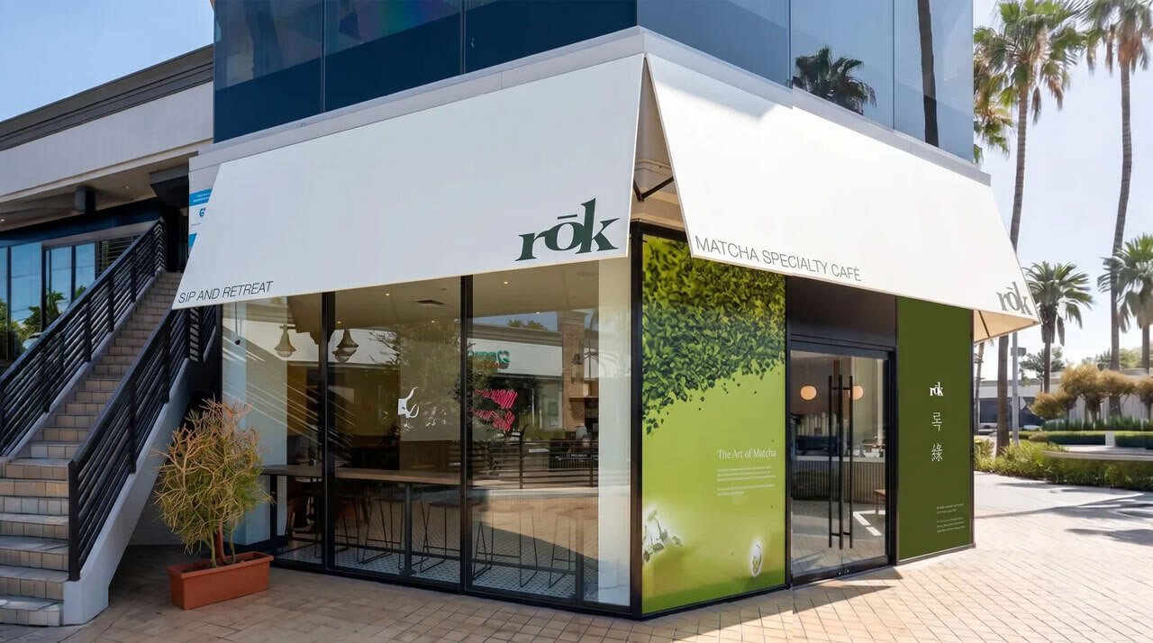 The rōk Studio City café on a corner, with a white awning and green matcha window panels