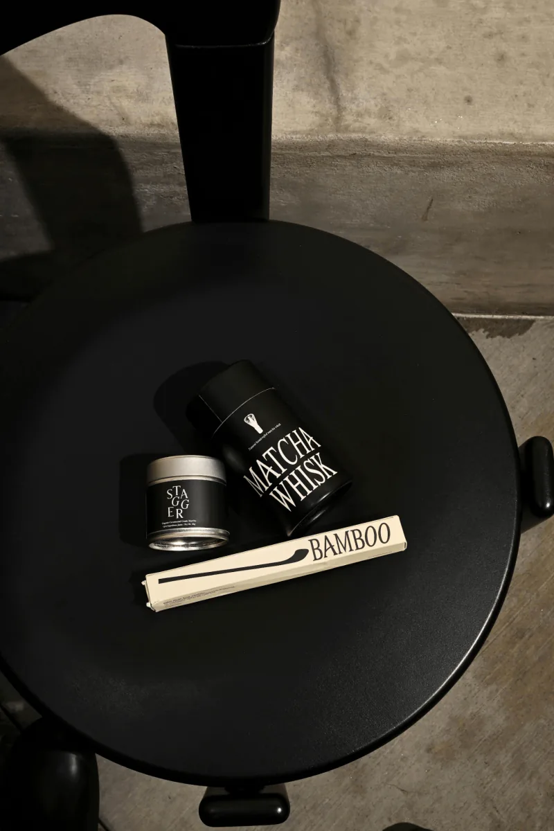 Stagger matcha tins, whisk tube and a boxed bamboo scoop on a black stool
